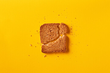 Single toast bread broken on a yellow background viewed from above. Top view. Whole wheat brown bread