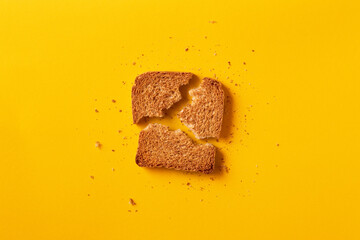Single toast bread broken on a yellow background viewed from above. Top view. Whole wheat brown bread