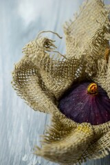 Bright purple luscious figs wrap in fabric on a gray wooden background. 