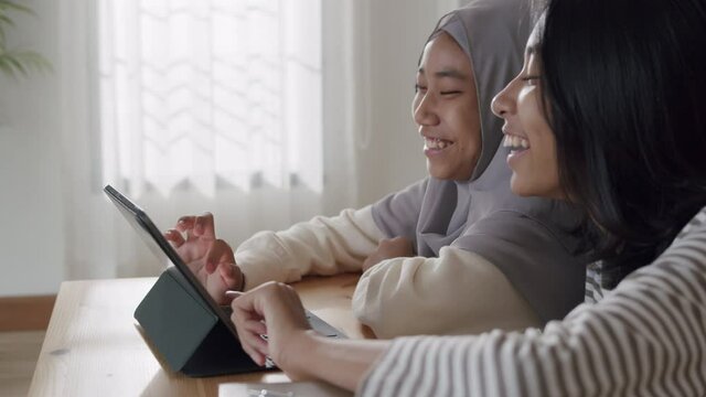 Happy Asian two girl using tablet Together while sitting in room at home