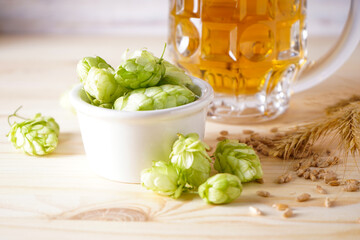 Hops and beer on a wood background, close-up