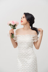 Beautiful elegant Asian young lady holding rose bouquet and wearing skinny dress over white background.