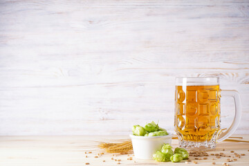 Light beer in a glass and hop on a wood background.