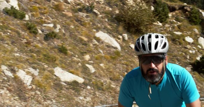 Slow motion of male road cyclist climbing a mountain pass pedaling hard. Effort, motivation, cycling training