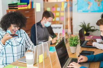 Happy young woman using mobile phone for sending audio messages - Multiracial people working inside coworking office wearing safety masks - Social distance concept - Focus on smartphone