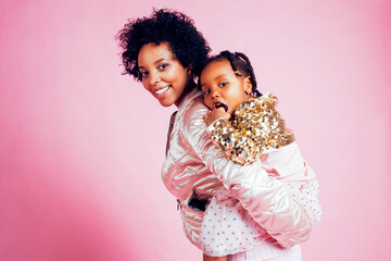young pretty african-american mother with little cute daughter hugging, happy smiling on pink background, lifestyle modern people concept