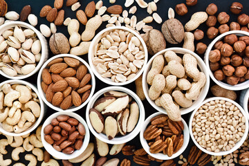 Colorful mix of various nuts: peanut and cashew, hazelnut and almond, pine nuts and  walnut; healthy diet snack; vegan food background