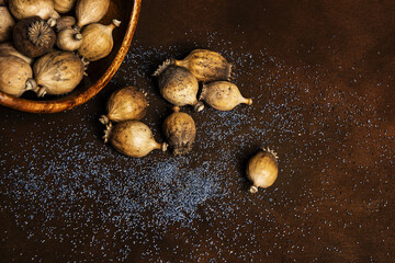 Bowl full of dry poppy pods with scattered poppy seeds