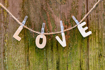 The inscription LOVE. from wooden letters on clothespins on a wooden background.
