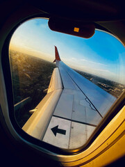 View from a landing airplane out the window of city at sunset