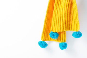 Yellow knitted scarf hanging on a white background. Close-up, selective focus. Horizontal orientation, copy space.