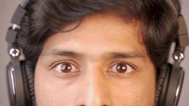 Close up, man listening music on headphones by closing eyes and suddenly opens in shock