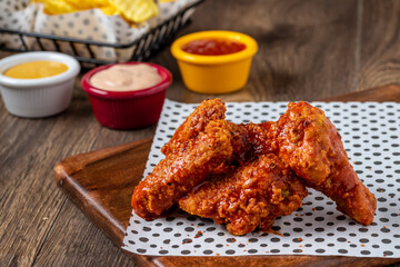 Baked chicken wings with sesame and sauce on wooden background