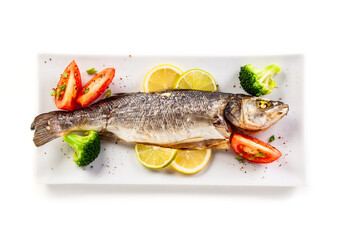 Fish dish - roasted trout with vegetables on white background
