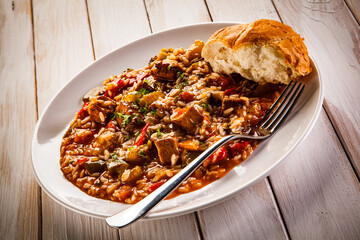 Roast pork meat with rice and vegetables on wooden background