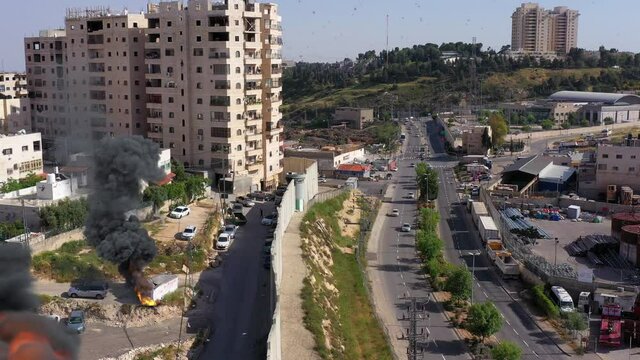 Israel and Palestine divided by wall with smoke and fire

Anata refugees Camp and Idf watch tower, aerial view
