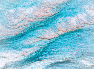Obraz premium Abstract blue, gray, orange and green background - layers of rocks exposed by sea in Northumberland