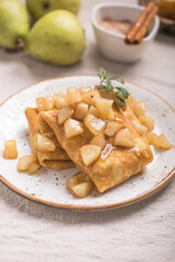 Thin pancakes (crepes) with apple filling, stuffed rolls, Russian traditional food for maslenitsa, French dessert, breakfast with tulips on mother's day