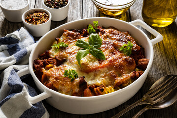 Pasta casserole with minced meat, mozzarella cheese and vegetables on wooden table