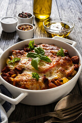 Pasta casserole with minced meat, mozzarella cheese and vegetables on wooden table