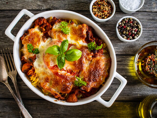 Pasta casserole with minced meat, mozzarella cheese and vegetables on wooden table