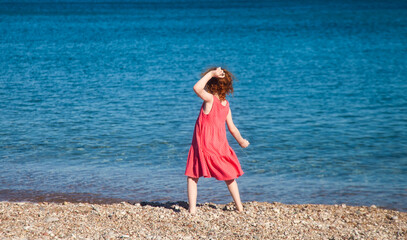 Little girl throwing pebbles at sea