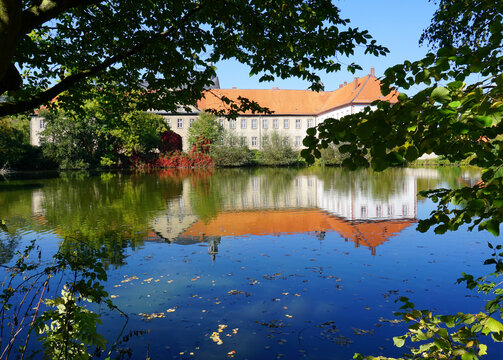 Blick durch die B&auml;ume &uuml;ber den Teich auf das Abteigeb&auml;ude der Klosteranlage in Lamspringe
