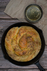 Cheese and zatar bread roll on cast iron pan, wooden table