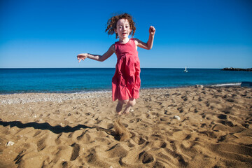 Cute little girl jumping in the sand
