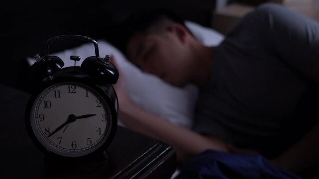 Depressed young Asian man cannot sleep from insomnia. Depressed man suffering from insomnia lying in bed.