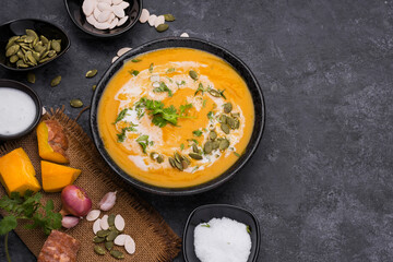 Curry or pumpkin soup with rice served in a ceramic platter on a black background - top view with writing space.