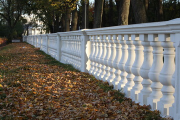 Stone balustrade long row on the colorful background of the autumn Park.Selective focus.Close-up of the Baroque style.Background texture.