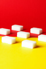 Cubo de azucar alineados con fondo de colores amarillo y rojo 