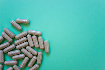 top view capsules of dietary supplements on green background. Layout white soft soluble. copy space. Concept of healthy life, vitamin.
