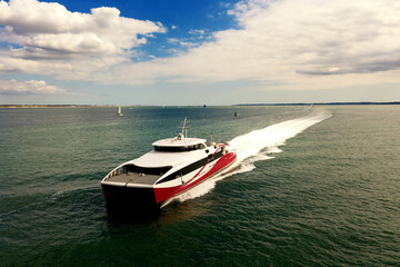 Aerial image of a fast passenger ferry on Southampton Water on a beautiful sunny day with clouds in...