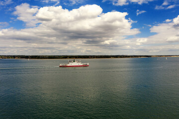 Fototapeta na wymiar Car ferry in Southampton Water on a beautiful sunny day with clouds in the blue sky. With space for text.