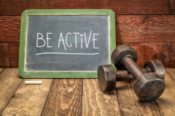 Be active, fitness and healthy lifestyle concept, white chalk writing on a slate blackboard with a...