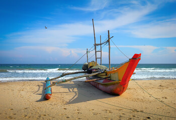 Beautiful scenic view - lonely traditional boat against the background of sea surf and dramatic blue sky in the wild beach of Tangalla, Sri Lanka island, Indian Ocean, South Asia