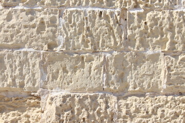 A photograph of an old stone wall in bright sunlight