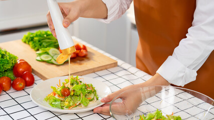 young Asian woman is preparing healthy food vegetable salad by Cutting ingredients on cutting board on light kitchen, Cooking At Home and healthy food concept
