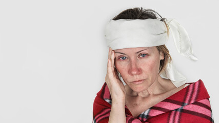 Sick and pale woman with red nose and eyes holding her head