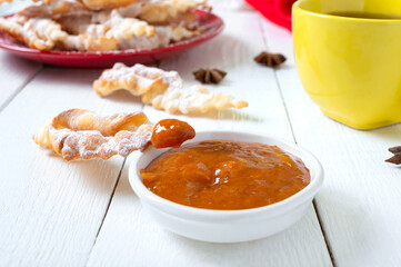 Tasty crispy deep fried cookies in powdered sugar with tea and jam on breakfast. Brushwood -  traditional treat at European festivals.