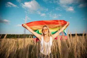 beautiful young female in sunglasses with lgbt flag in a field in summer