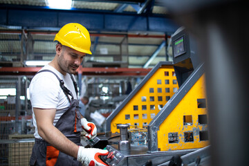 Portrait of factory worker working on industrial machine in production plant.