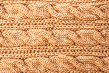 The texture of a beige knitted scarf close-up.