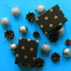 Christmas flat lay of silvery shiny Christmas balls, cones and gift boxes, horizontal background, festive mood, space for text, selective focus