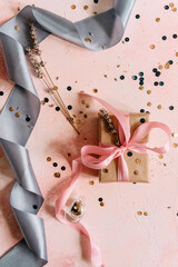 Gift or present box and stars confetti on pink table top view. Flat lay composition 