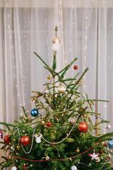 A close-up of the top of a living Christmas tree decorated with holiday decorations.