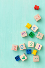 Colorful plastic and wooden cubes with numbers scattered on a turquoise wooden table. Top view of children's toys and other equipment. Educational games for children. Cubes with numbers 2021.