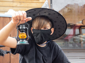 Boy with Halloween lattern in a black face mask